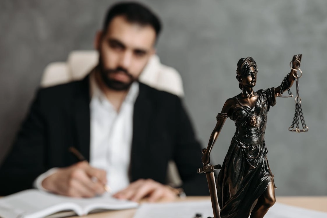 Justice statue with legal documents nearby.