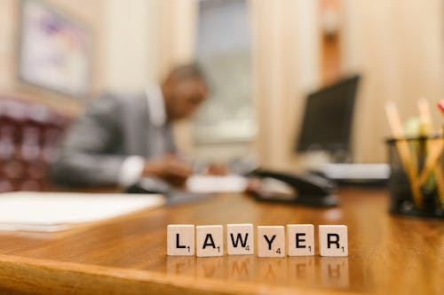 Scrabble tiles spell 'LAWYER' on desk.