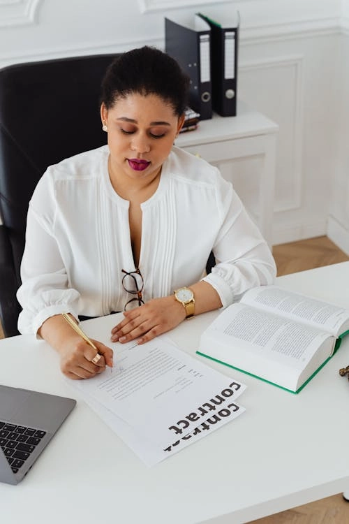 Person writing on contract document